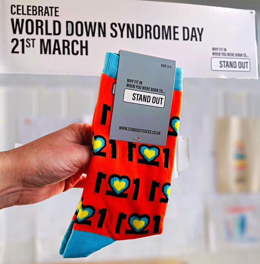Hand holding up a pair of Stand Out Down Syndrome Awareness Socks