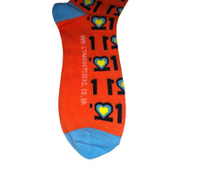 Load image into Gallery viewer, Man with Glasses on and orange jumper, Smiling and holding a pair of colourful Down Syndrome Awareness Socks
