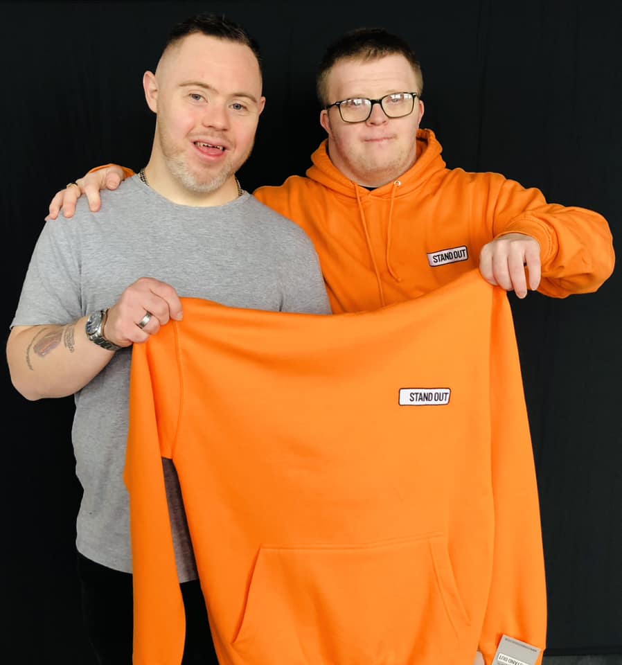 Oliver & Ross of Stand Out Socks Holding a Stand Out Hoodie and Smiling 