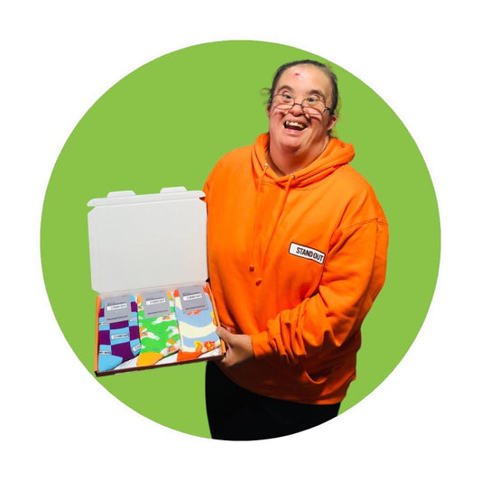 Martha from Stand Out Socks Holding a Box of Socks and smiling