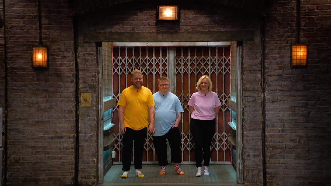 2 men and 1 lady in bright coloured tshirts standing in a lift