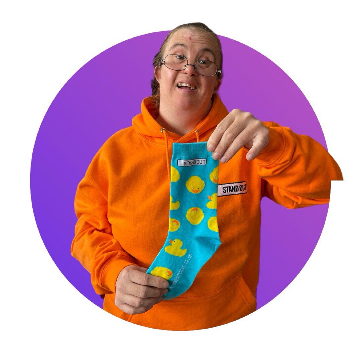 A Lady who has Down Syndrome holding up a pair of blue socks with rubber ducks socks 