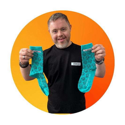 Man holding two blue socks with a brand logo against an orange and yellow background