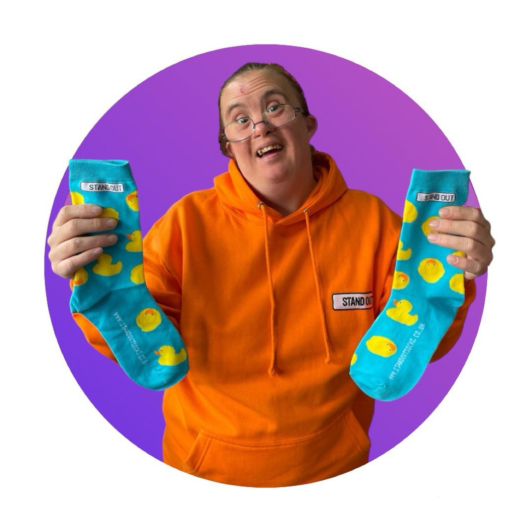 Lady holding up a pair of blue socks with rubber ducks socks 