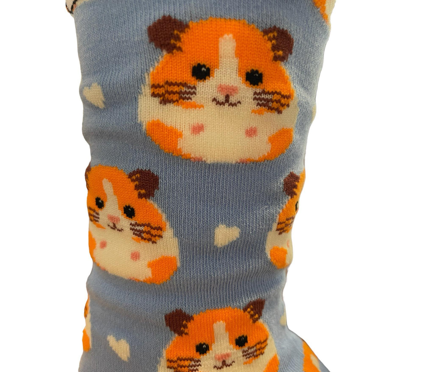 Light blue socks featuring a cute guinea pig pattern, created by Stand Out Socks. The socks display a playful design with orange and white hamster faces and small white hearts scattered throughout. The words "STAND OUT" are visible on the cuff and the company's website is printed on the sole.