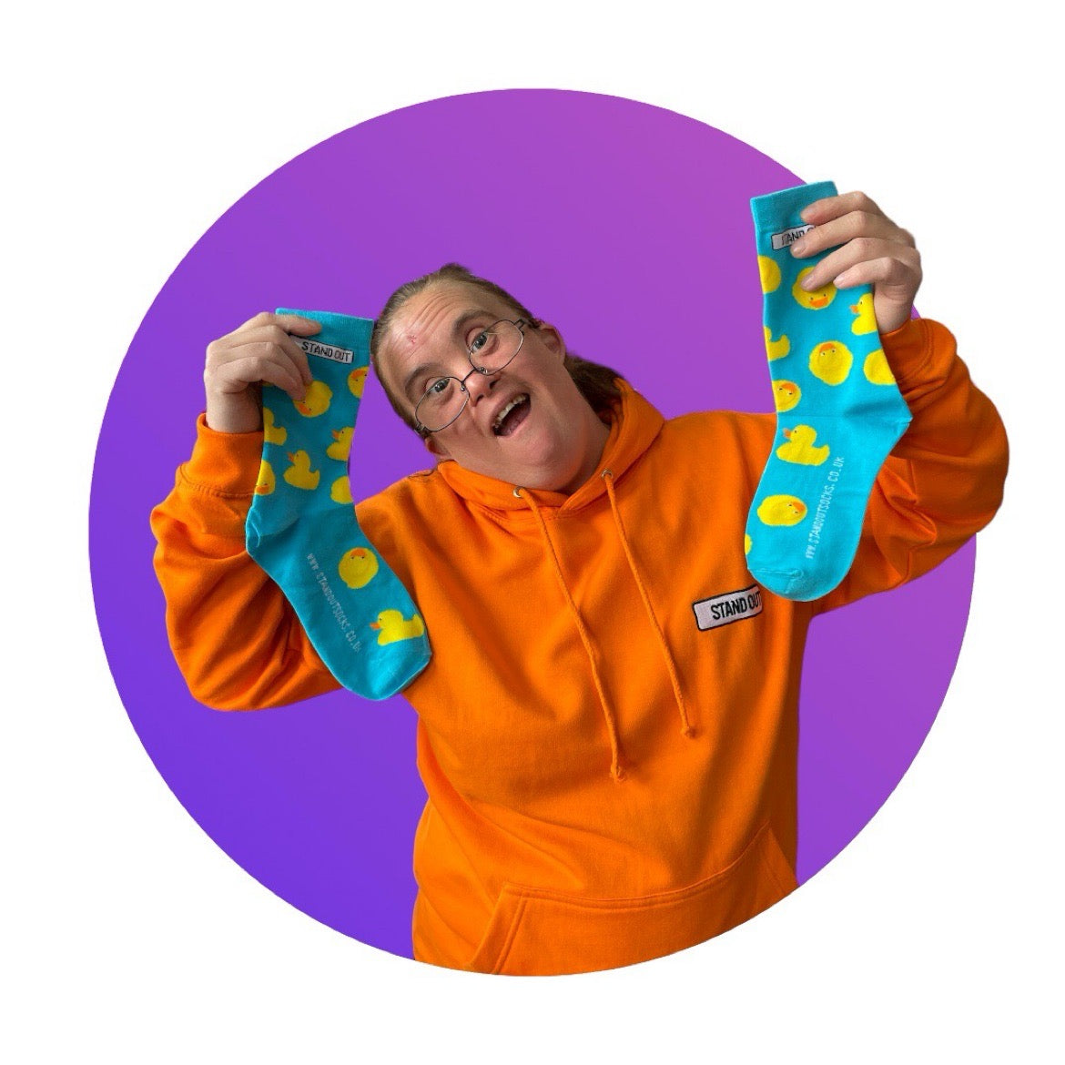 A Lady who has Down Syndrome holding up a pair of blue socks with rubber ducks socks 