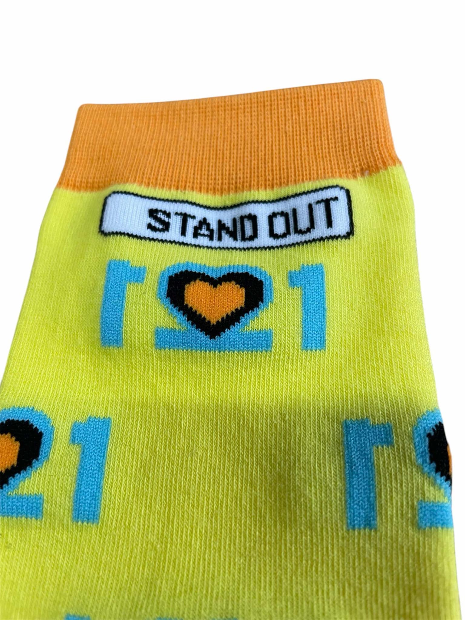 The Official World Down Syndrome Day Stand Out Socks which are yellow, blue and orange, feature a design that incorporates the number 21 mirrored to form three hearts at the centre, symbolising the triplication (trisomy) of the 21st chromosome, which causes Down syndrome.