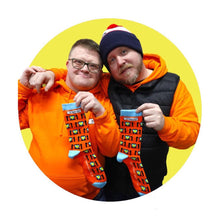 Load image into Gallery viewer, 2 Men, one with  with Glasses on and orange jumper, and the other with a hat on, Smiling and holding a pair of colourful Down Syndrome Awareness Socks
