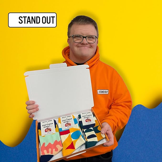 3 Pairs Of Funky stand Out Socks With Geometric Patterns in a box being held up by Ross the cofounder of stand out socks